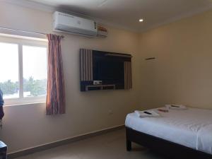 a bedroom with a bed and a tv and a window at Hotel Strawberry Grand in Rāmeswaram +10 photos