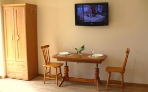 a table with two chairs and a tv on the wall at Apartamenty Nad Jeziorem in Postawele