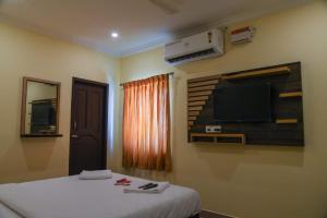 a bedroom with a bed and a flat screen tv at Hotel Strawberry Grand in Rāmeswaram
