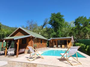 a house with a pool and two chairs and a cabin at PARADISO pool&house in Prosek
