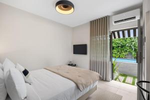 a white bedroom with a bed and a television at The Weekender Hotel in San Juan