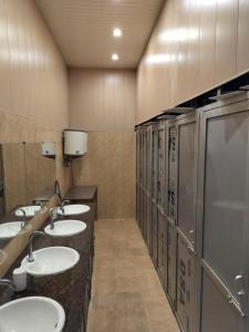 a public bathroom with four sinks and a row of urinals at AC Dormitory in Varanasi