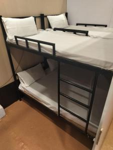 a bunk bed with white sheets and pillows on it at AC Dormitory in Varanasi