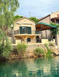 a house with a balcony next to a body of water at Skadar Lake Hideaway in Karuč