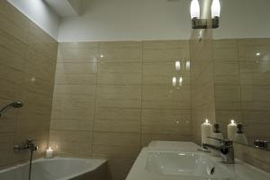 La salle de bains est pourvue d'un lavabo, d'une baignoire et de bougies. dans l'établissement Károlyi Garden | hostAID, à Budapest