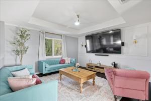 a living room with blue and pink furniture and a tv at French-Style 5-BD w/ Pool, Playground, Cinema in Lewisville