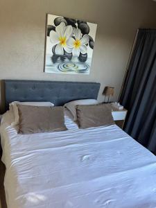a bed with white sheets and a picture of flowers at Les Cigales in La Crau +21 photos