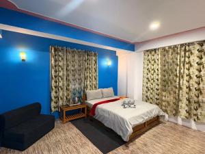 a bedroom with blue walls and a bed and a couch at Mayal Lyang Lachung in Mangan +20 photos