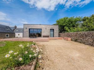 a house with a stone wall and a yard at La Villetta Penmarch in Penmarch