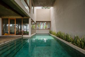 an indoor swimming pool in a house with blue water at The Coast Sri Lanka, Bentota in Bentota
