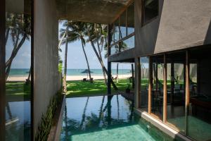 an external view of a house with a swimming pool and the ocean at The Coast Sri Lanka, Bentota in Bentota