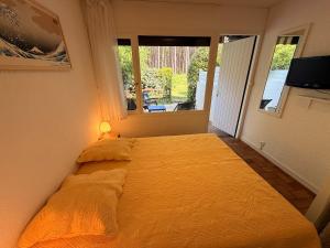 a bedroom with a large yellow bed with a window at Le cottage landais in Lit-et-Mixe