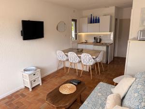 a living room with a table and chairs and a kitchen at Le cottage landais in Lit-et-Mixe