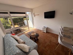 a living room with a couch and a flat screen tv at Le cottage landais in Lit-et-Mixe