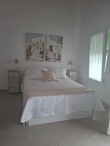 a white bedroom with a large bed with white sheets at La corrala de la calle Sol in Jerez de la Frontera