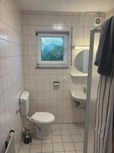 a bathroom with a toilet and a sink and a window at Monteurhome Monteurzimmer A7 A5 in Niederaula