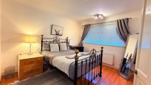 a bedroom with a bed and a dresser and a window at Stunning Modern Cozy 5 star 3 bedroom house-Free Parking Greater London Metro Stations hosted by Tony in Catford