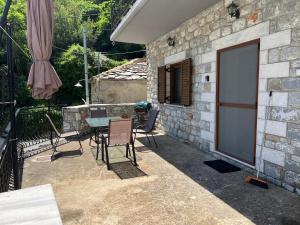 a patio with a table and chairs and a stone wall at Casa Koutrea in Kastanéa