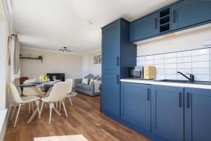 a kitchen with blue cabinets and a table with chairs at Sea Point - 2 bed apartment in Saltcoats