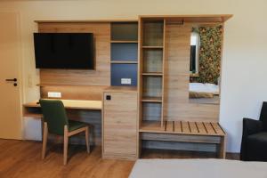 a room with a desk and a tv and a bedroom at A&E Hotel Friedrichshöhe in Braunschweig