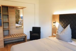 a bedroom with a bed and a chair and a mirror at A&E Hotel Friedrichshöhe in Braunschweig