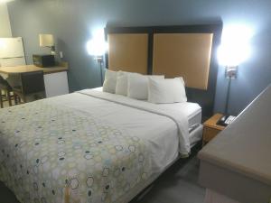 a hotel room with a large bed with white sheets at HomeTowne Studios by Red Roof Chantilly in Chantilly