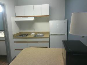 a small kitchen with a refrigerator and a sink at HomeTowne Studios by Red Roof Chantilly in Chantilly