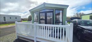 a small house with a white fence and a porch at LJ Holiday Let in Middleton