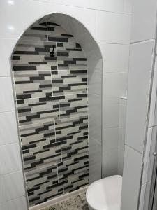 a bathroom with a toilet and a tile wall at Chambre privée Moret Sur Loing in Moret-sur-Loing +25 photos