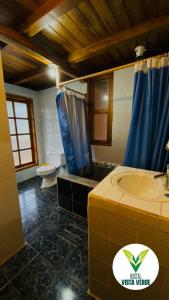 a bathroom with a sink and a toilet and blue shower curtain at Hostal Vista Verde in Mindo +66 photos