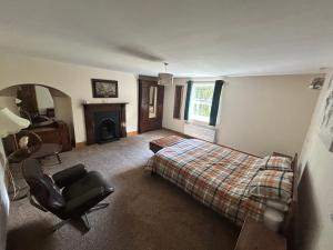 a bedroom with a bed and a chair and a fireplace at Herberts Cottage in Wormegay