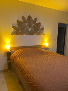 a bedroom with a bed with two lights on the wall at Maison avec piscine proche plage in Les Trois-Îlets +5 photos