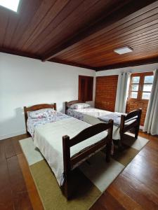 a bedroom with two beds and a wooden ceiling at Chalé Deruci in Nova Friburgo