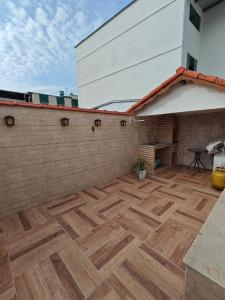 a patio with a wooden floor next to a brick wall at Chalé Deruci in Nova Friburgo
