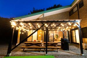 a picnic table under a pergola with lights at HARMONIA 那須 Nas-MAX26名-川遊び-BBQ-カラオケのできる宿 in Nasu