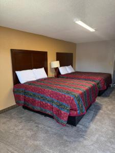 a hotel room with a large bed with a red blanket at Crown Lodge in Kansas City