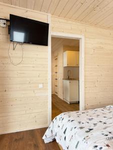 a bedroom with a bed and a flat screen tv on a wall at Medsukys - Namukai Dviem in Griniūnai