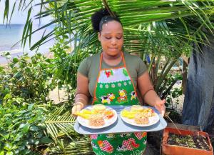 a woman in an apron holding two plates of food at cabaña malambo in Termales - agua caliente - nuqui