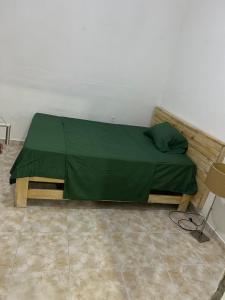 a bed with a green sheet on it in a room at T1 centro da cidade cif in Luanda
