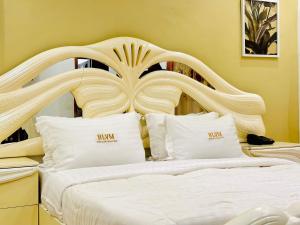 a bedroom with a white bed with a wooden headboard at hotel la valeureuse mère in Yaoundé