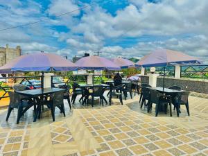 a group of tables and chairs with purple umbrellas at hotel la valeureuse mère in Yaoundé