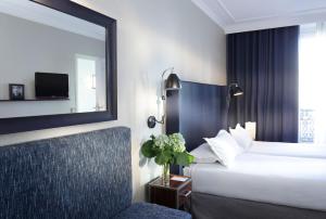 a hotel room with a bed and a mirror and a chair at Hôtel Londres et New York - Teritoria in Paris