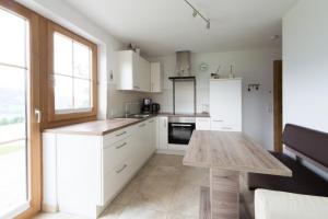 une cuisine avec des placards blancs et une table en bois dans l'établissement Appartement Kufsteinblick, à Haus im Ennstal