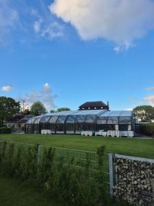 a large glass building in a field with some animals at De vijverhut in Schagen