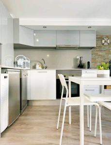 a kitchen with white cabinets and a white table and chairs at NEW - Casa Rocha in Sesimbra