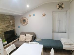 a bedroom with a bed and a couch and a tv at NEW - Casa Rocha in Sesimbra