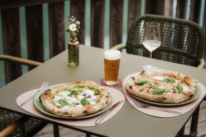 two pizzas sitting on a table with a glass of beer at Antholzer Wildsee Haus in San Giuseppe in Anterselva