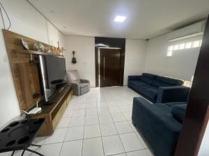 a living room with a blue couch and a tv at Casa in Petrolina