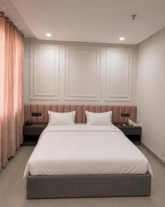 a bedroom with a large bed with white sheets at Hotel Golden Plaza in Amritsar