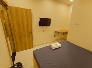 a small room with a bed and a tv on the wall at Hotel Mahakal Ujjain Prime in Ujjain
